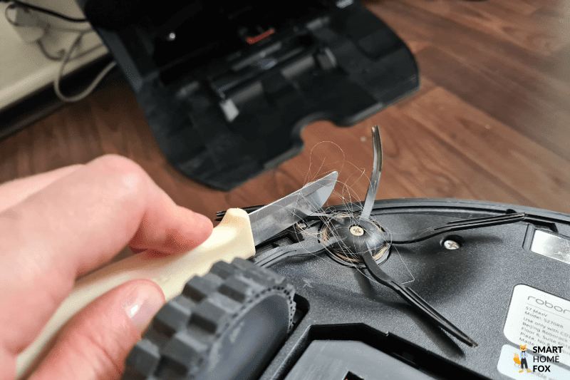 Haare werden von der Seitenbürste des Roborock S7 MaxV Ultra mit Hilfe eines Messers entfernt